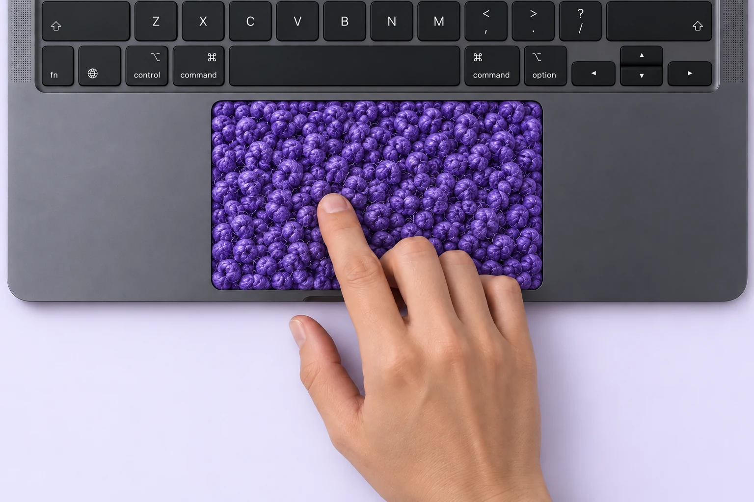 A finger touching a MacBook trackpad illustrated as purple bouclé fabric to represent tactile feedback